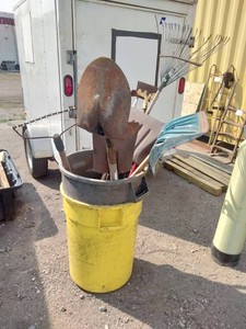 Yellow and gray utility container holding an assortment of long-handled yard and garden tools