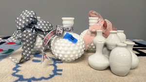 glass hobnail bottle paired with a cluster of small, bulbous white bud vases