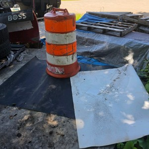 LARGE ORANGE TRAFFIC CONE AND SOME KIND OF TARP