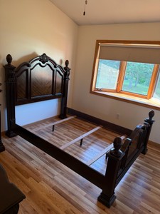 Traditional dark wood bed frame with an arched headboard, decorative shell carvings, and turned posts
