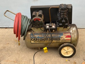 Campbell Hausfeld Cast Iron Series air compressor (20-gallon horizontal model) equipped with an electric motor, pressure switchmanifold with dual gauges, and a tank-mounted handle with wheels