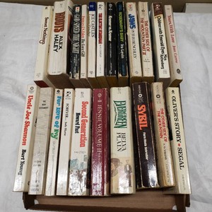 Box of Assorted Paperback Novels by Various Authors featuring various titles such as Roots by Alex Haley, Rosemarys Baby by Ira Levin, and Jaws by Peter Benchley