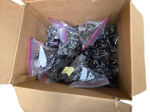 large cardboard box filled with loose, black metal binder clips of varying sizes,