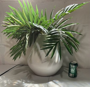 White ceramic vase with artificial palm arrangement