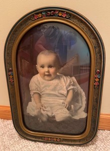 antique 1920s portrait of a seated baby housed in an arched, ornate gesso wood frame with convex bubble glass
