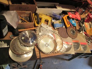 Large supply of assorted saw blades, sanding discs, screwdrivers, metal files, measuring supplies, electric staple gun, rubber mallet and other misc on workbench as shown in pics