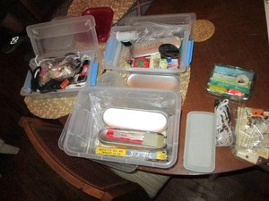 Seamstress survival kit including safety pins, threads, needles, buttons, shoelaces, thimble, pin cushion and other sewing notions, all loaded into a variety of lidded storage containers
