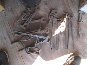 5-gallon bucket containing vintage pipe wrenches, forging tools and speed wrench