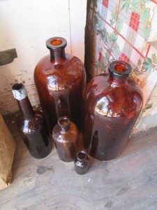 Vintage amber glass bottles of assorted size and style tallest being approx 14in