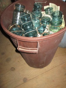26-gallon Rubbermaid roughneck trash can loaded with colored glass canning jar canisters with lids
