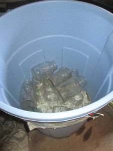 26-gallon Rubbermaid roughneck trash can with lid containing assorted glass canning jars