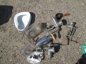 Collection of vintage metal meat grinders, glass bottles with carrying handle, bed pan and horse grooming brush with lidded tote