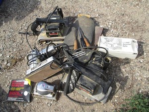 Vanity of vintage sanders, chisels and sandpaper in covered tote with metal belt sander stand