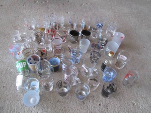 Collection of vintage shot glasses in varying styles and advertisements