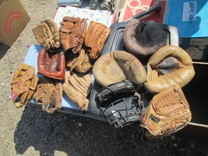 Variety of vintage baseball gloves and mitts plus a face mask