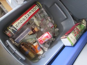 Covered Tote containing a variety of vintage glass bottles, tins, cans and Copenhagen retail chew dispenser