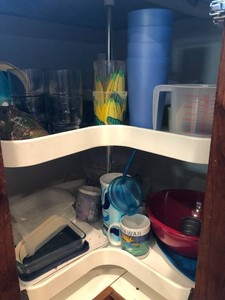 Assorted plastic cups, storage containers, measuring cup, serving trays and more all in cupboard