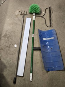 Garden tools including a rake with no handle, snow pusher with no handle, and brush with metal handle and green bristles