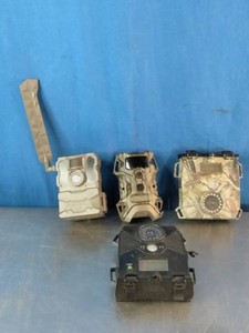 A a collection of four different outdoor wildlife and trail cameras used for hunting or security monitoring.