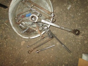 Metal drain pan with assorted wrenches, ratchets and other tools