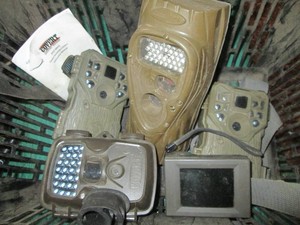 Basket of assorted trail cameras and no trespassing signs