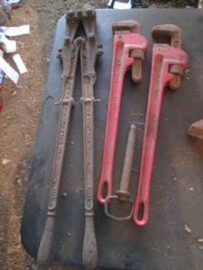 Large bolt cutter and pair of large pipe wrenches