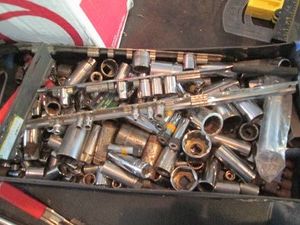 Metal tool tray full of assorted size and style deep and shallow sockets and rail clips