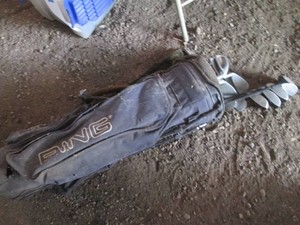 Vintage black golf bag with assorted clubs and drivers