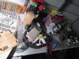 Content on tabletop to include solar auto fan, light bulbs, Thermos, ice scrapers, coat hooks, hanging file folders, enamelware roaster pan, suet feeder, pig mug, flashlights and more