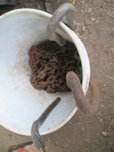 Bucket with misc chains, hooks and cats paw pry bat