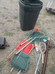 Variety of fishing nets and padded seat cushions with Rubbermaid rolling trash can