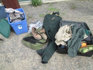 Covered Tote, suitcase and mesh front gear bag containing a variety of mens size clothing, size 11 steel toe boots, neoprene waders, seat cushion and more