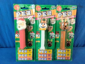 Three vintage holiday PEZ candy dispensers featuring Santa Claus, a snowman, and a reindeer in green blister packaging