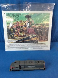Vintage HO scale model of a Southern Pacific diesel locomotive (resembling an EMD GP or SD series engine) alongside a bagged promotional sign