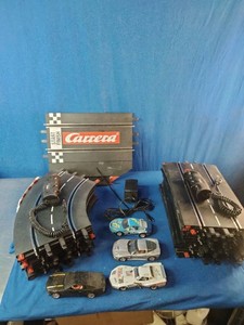 Carrera slot car set with stacked track pieces, hand controllers, a power supply, and four assorted model cars.
