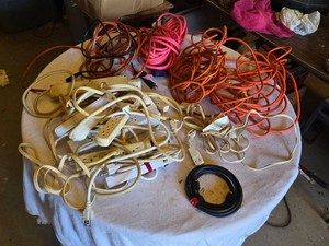 Extension cords and power strips including orange, pink, and black extension cords, and assorted white power strips