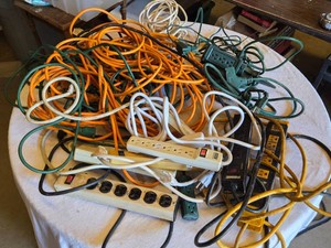 Extension cords and power strips including orange, green, and white cables