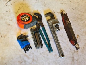 Tape measure,  Rigid Aluminum Pipe Wrench, hex keys, and saw blades