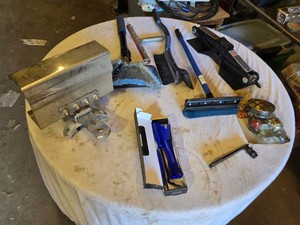 Lot of garage items with miscellaneous tools and accessories including a hitch, brushes, a jack, an auto trim removal kit, and a reflective light