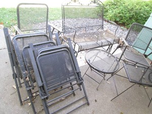 Patio furniture set includes 1-Black mesh metal 2-person glider bench with 6-matching folding chairs and 2-side tables