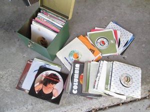 Metal lidded box containing a wide variety of 45s vinyl record albums