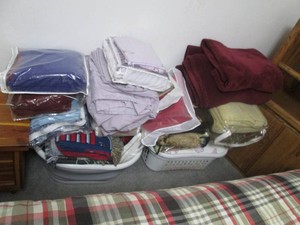Large assortment of bed linens mostly bed sheets and blankets