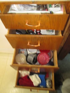 Drawer organizer with stainless steel flatware, variety of knives, jar opening aids, batteries, hand towels, food storage containers with lids and more