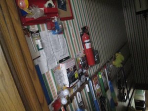 Large variety of cleaning supplies, hooks, , cord managers, power cutter, office supplies and more content on walls of basement stairwell