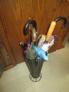Freestanding metal umbrella stand with assorted size and style umbrellas