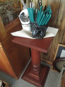 Wood pedestal plant stand with metal utensils holders and assorted flatware