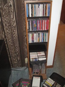 Laminate multimedia storage tower woth assorted music CDS, tape cassettes and misc travel cases