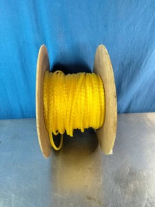 A spool of bright yellow polypropylene utility rope wound on a wooden reel.