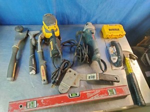Container with DeWalt random orbit sander, a teal corded angle grinder, a red Milwaukee spirit level, and more