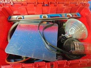 Red storage container filled with a variety of mixed equipment and tools